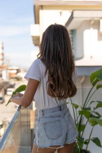 Una donna in pantaloncini di jeans che sta su un balcone di Hotel The Sea a Rimini