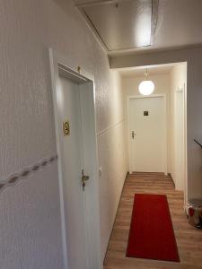 un pasillo con una alfombra roja y una puerta blanca en Alex -Lounge -Sportsbar -Smokerlounge, en Otterbach