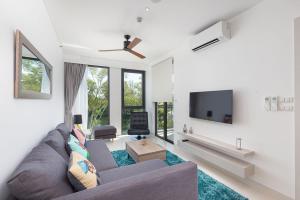 een woonkamer met een bank en een tv bij Cassia Residence Laguna Phuket Holiday Rental Apartment, Bang Tao Beach in Phuket