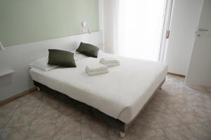 ein großes weißes Bett mit zwei grünen Kissen darauf in der Unterkunft Hotel The Sea in Rimini