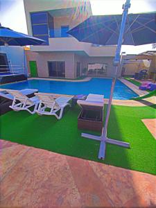 a pool with two picnic tables and an umbrella at Tala Villa in Amman