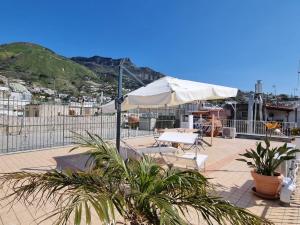 un patio con sombrilla y 2 sillas y plantas en Bella D'Estate - 10 minutes from the beach en Isquia