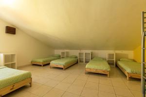 a room with four beds with green sheets at Pineapple Surf House in Peniche