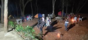 a group of people standing around a campfire at night at Hotel Hilltone- panorama bungalow matheran in Matheran