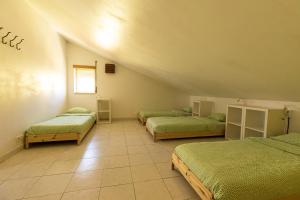 a room with three beds with green sheets at Pineapple Surf House in Peniche