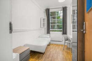 een witte kamer met een bed en een raam bij Bowden Court (Notting Hill) in Londen