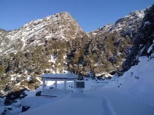 a snow covered mountain with a building in the snow at Himrab Chopta Resort in Chopta +21 photos
