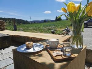 een tafel met een vaas en twee bekers en een vaas met bloemen bij Sternstube – Appartement mit traumhaftem Weitblick in Freyung