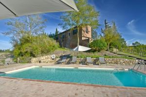 a swimming pool in front of a house with an umbrella at Podere Le Crete in Montepulciano