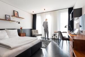 uma pessoa em pé num quarto de hotel com vista para a janela em Brera Serviced Apartments Munich Schwabing em Munique
