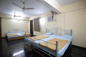 a bedroom with two beds and a ceiling fan at Hotel Hilltone- panorama bungalow matheran in Matheran