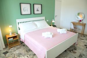 a bedroom with a pink bed with two towels at Villa Ravanica in Marina di Ragusa