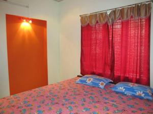 a bedroom with a bed with red curtains and blue pillows at Gladsvilla in Mangalore +8 photos
