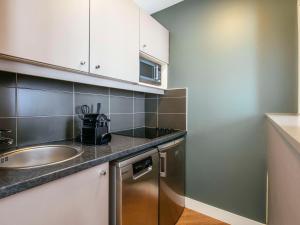 a small kitchen with a sink and a dishwasher at Aparthotel Adagio Paris Buttes Chaumont in Paris