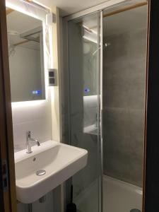 ein Bad mit einem Waschbecken und einer Glasdusche in der Unterkunft 17e straatje in Elburg