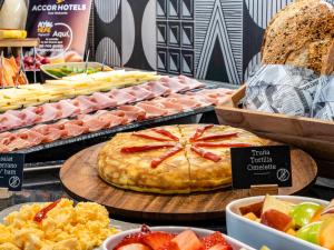 a buffet of food with a pizza on a table at ibis Styles Barcelona City Bogatell in Barcelona