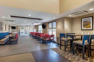 a dining room with tables and red chairs at Comfort Inn & Suites in Edgewood