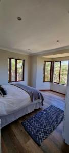 a bedroom with a large bed with windows and a rug at Zoete Inval - 3 Bedroom Self Catering Home. in Langebaan