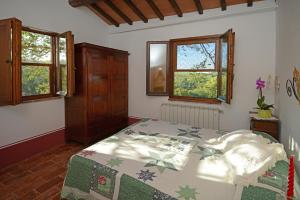 a bedroom with a bed and two windows at Podere Le Crete in Montepulciano