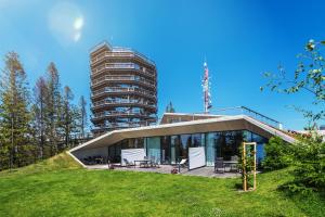 a house on a hill with a tall building in the background at Apartmány PANORAMA Bachledka in Ždiar