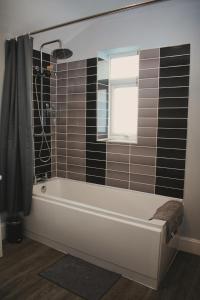 Cosy 2 Bedroom Flat in Sunderland في سندرلاند: حمام مع حوض استحمام ونافذة