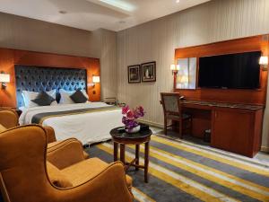 ein Hotelzimmer mit einem Bett und einem Flachbild-TV in der Unterkunft Shaty Alhayat Hotel Suites in Dschidda