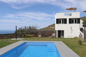 a villa with a swimming pool in front of a house at Casa das Rosas by Homing in Arco da Calheta