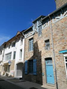 an old stone building with blue doors on a street at maison quiberonnaise in Quiberon