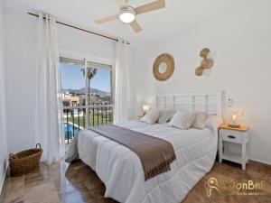 biała sypialnia z łóżkiem i dużym oknem w obiekcie Apartamento cerca de la playa en las lagunas de Mijas w mieście Fuengirola