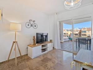 salon z telewizorem z płaskim ekranem i stołem w obiekcie Apartamento cerca de la playa en las lagunas de Mijas w mieście Fuengirola
