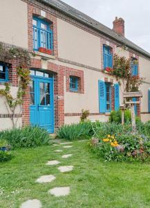 uma casa de tijolos com uma porta azul e um quintal em La Ferme de Plénoise Chambres d'hôtes 