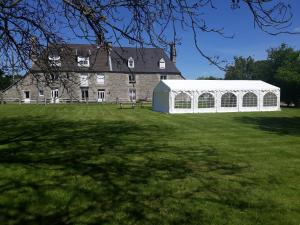 een witte tent in een veld voor een gebouw bij Gîtes de L'Aumondière in Condé-sur-Noireau