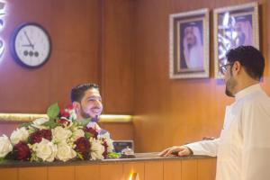 Dois homens atrás de um balcão com flores. em Shaty Alhayat Hotel Suites em Jeddah