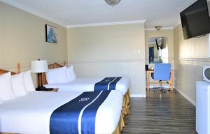 a hotel room with two beds and a flat screen tv at Omeo Suites Glass Beach in Fort Bragg