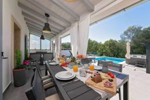 ein Esszimmer mit einem Tisch und Stühlen auf einer Terrasse in der Unterkunft Villa LULU with heated pool, sauna & hot tub in Labin