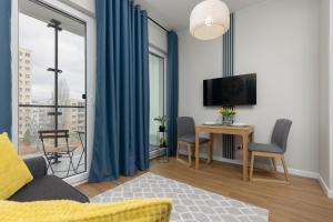 Elle comprend un salon avec un canapé et un bureau avec une télévision. dans l'établissement Cozy Apartments Warsaw Wola Kasprzaka by Noclegi Renters, à Varsovie