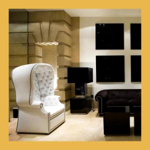 a living room with a white chair and a television at Hotel Clarin in Oviedo