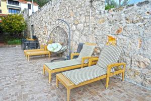 a group of chairs sitting next to a stone wall at Villa Katarina in Dubrovnik
