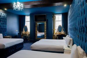 a blue room with two beds and a mirror at The Dixie Dean Hotel in Liverpool