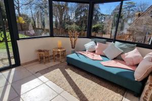 a living room with a blue couch and large windows at Jardins de Mélusine - Maison en pierres 