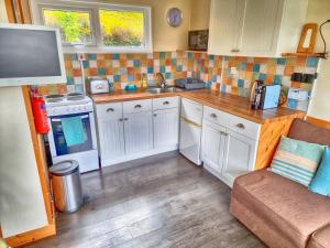 a small kitchen with white cabinets and a sink at Caswell Beach Chalet 70 located in Gower Peninsula in Swansea