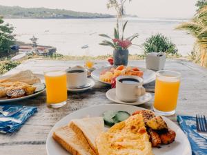 a table with plates of breakfast foods and orange juice at Lebaoh Nusa Cottage in Nusa Lembongan