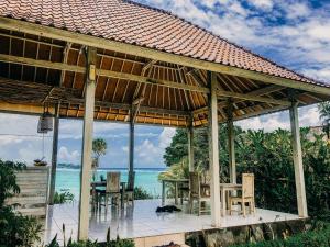 - un pavillon avec une table et des chaises et l'océan dans l'établissement Lebaoh Nusa Cottage, à Nusa Lembongan