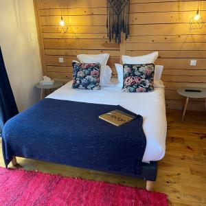 una camera da letto con un letto con una coperta blu e cuscini di O Lodge a Cleppé