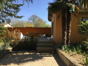 eine Terrasse mit einer Palme, einem Tisch und Stühlen in der Unterkunft Logis Hôtel O Lodge in Cleppé