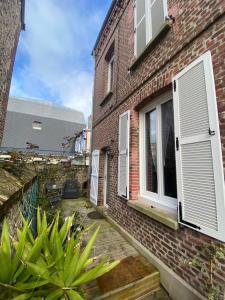 Cette maison en briques est dotée de volets blancs et d'une terrasse. dans l'établissement Chambre D'hôte Villa Maurice, à Étretat