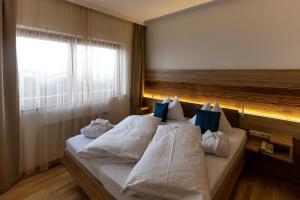 Schlafzimmer mit einem Bett mit weißer Bettwäsche und blauen Kissen in der Unterkunft Hotel Turracherhof in Turracher Hohe