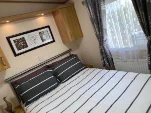 ein Schlafzimmer mit einem Bett mit zwei Kissen und einem Fenster in der Unterkunft B7 Millfields, Ingoldmells - 3 Beds, Ramp Access, Pet Friendly in Ingoldmells