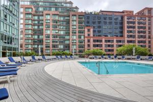 a swimming pool with blue lounge chairs and buildings at Hells Kitchen 1BR w Doorman nr Central Park NYC-525 in New York