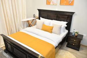 Bett mit weißer und orangefarbener Bettwäsche und Kissen in der Unterkunft Sky Studio in Nairobi